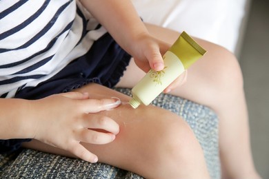 little toddler girl applying lotion on her legs