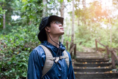 asian man carrying a backpack hiking in the rainy season