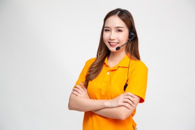 portrait of happy smiling asian woman telemarketing operator in orange delivery uniform with headphone isolated on white background, call center or customer service concept