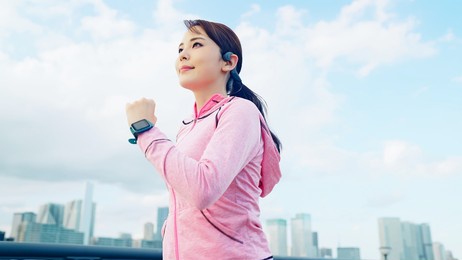 young asian woman jogging in front of the city.