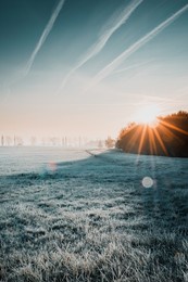 first sunlight on a early cold winter morning with frozen grass landscape and bright foggy glow. misty winter morning with orange sunrise countryside landscape