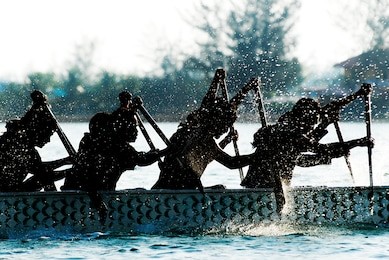 dragon boat participant silhouetted by backlit.