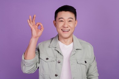photo of reliable funny korean man show okey fingers well done gesture isolated violet color background