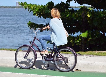 young woman bicyclist waiting for the venetia causeway drawbridge of open for motor and bicycle traffic in `miami beach,florida.
