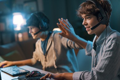 cheerful friends playing online video games together and winning, they give a high five