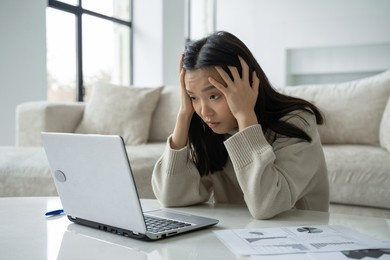 tired, exhausted asian woman with a laptop, problems with the project, feeling depressed, laziness in the home office in the living room