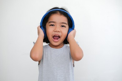 a five year old girl is listening music on her headphone.