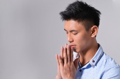 in casual clothes close up portrait of young man wearing in blue jeans shirt holding hands in praying gesture

