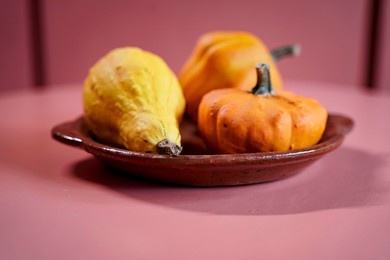 three decorative pumpkins on a ceramic plate.