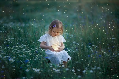 little white girl sits in an evening glade with fireflies