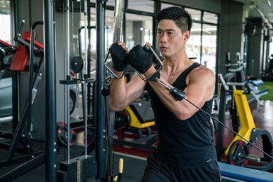 muscular man wearing sportswear using strength tools doing bodyweight exercise for bodybuilding workout in fitness gym. fitness training, bodyweight building and workout exercise concept