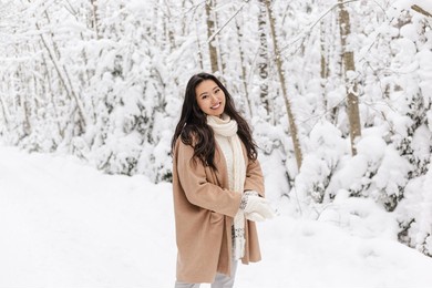 cute asian girl standing smiling in winter forest. snowy winter day. lovely girl