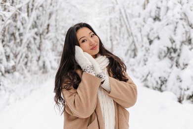 cute asian girl standing smiling in winter forest. snowy winter day. lovely girl