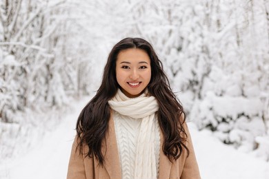 cute asian girl standing smiling in winter forest. snowy winter day. lovely girl