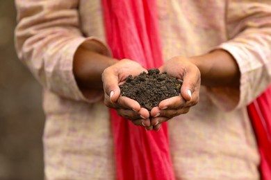 indian farmer holding black soil in hand.