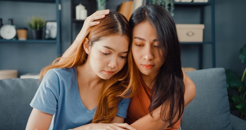 asian women teenager embracing to calm her sad best friends from feeling down from breakup with boyfriend in living room at home. friendship counseling and care, unhappy girl support her girlfriend.