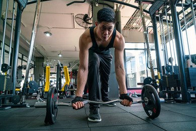 muscular man wearing sportswear using dumbbell bodyweight doing exercise for bodybuilding workout in fitness gym. fitness training, bodyweight building and workout exercise concept