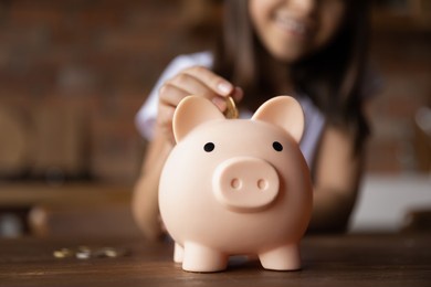 kid putting coin into pink piggy bank. happy girl saving money, cash for purchase learning economy, business, investment, planning future counting budget. financial education concept. close up