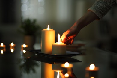 close up of woman hand lighting candles in the dark night at home