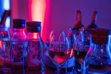 glasses of wine and snacks on a bar table in night club blue and red neon lights. party or nightlife entertainment with copy space