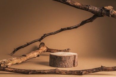 rustic podium of cylinder shape stump, and dried branches on beige background. product, cosmetic, perfume, jewellery mock up.