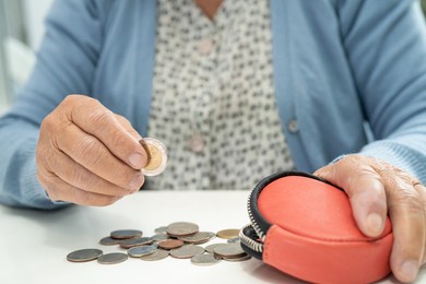 asian senior or elderly old lady woman holding counting coin money in purse. poverty, saving problem  in retirement.