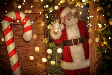 portrait of a joyful smiling santa claus in a wooden house among christmas lights and festive decorations. merry christmas and happy new year!