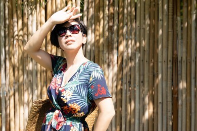 a beautiful stylish asian woman wearing 100% uv light eyes protection sunglasses, raise her hand to block out sunlight to avoid ultraviolet rays over exposure. sunscreen, spf, facial skincare, outdoor