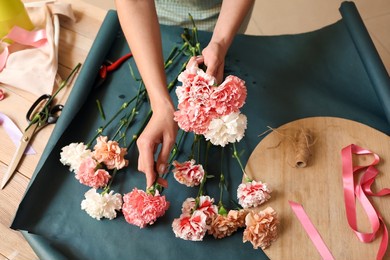female florist making bouquet with carnation flowers in workshop