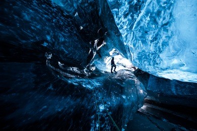 mountain climber standing inside an icecave in a glacier in iceland
