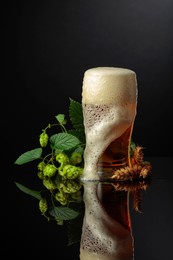 beer with hops and barley on a black reflective background.