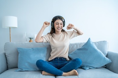 asian funny woman listen to music and dance on floor in living room. attractive beautiful young girl put on headphone feeling happy to spend leisure time at home and enjoying weekend activity in house