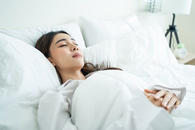 asian beautiful comfort girl in pajamas get up from sleep in bedroom. attractive young woman lying down on bed feel happy with cozy pillow and blanket enjoy early morning after wake up in room at home