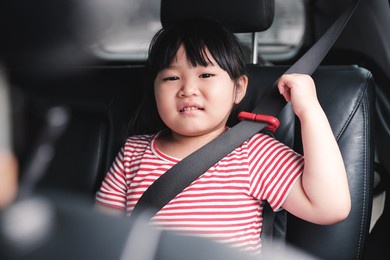 cute asian female child girl smiling cheering with fist up in the air excited for traveling holiday vacation weekend play day, sitting in car with seatbelt on for safety and care. transport automobile