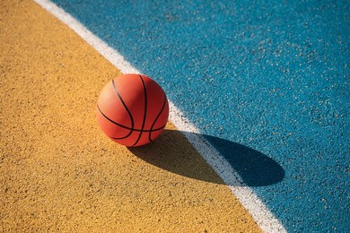 orange basketball ball laying at the colored track at the street stadium