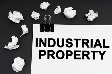 industrial concept. on a black background, there are crumpled pieces of paper and paper with the inscription - industrial property
