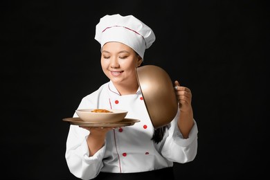 beautiful asian chef with dish on dark background