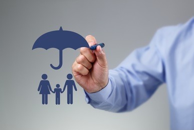 businessman hand drawing an umbrella above a family concept for protection, security, finance and insurance