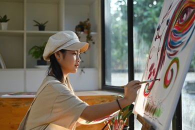photo of an adorable girl painting on drawing canvas in the modern art studio.