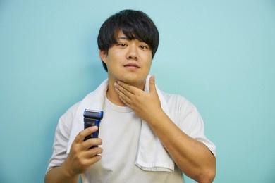 asian man in his twenties shaving with a towel on a white shirt