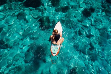 surf girl on surfboard wait wave in transparent ocean. aerial view with surfer woman