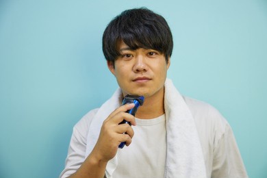 asian man in his twenties shaving with a towel on a white shirt