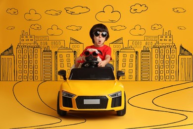 cute little boy with his dog in toy car and drawing of city on yellow background