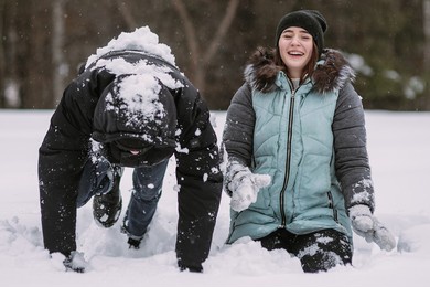 happy couple of teenagers having fun playing in snow in winter forest