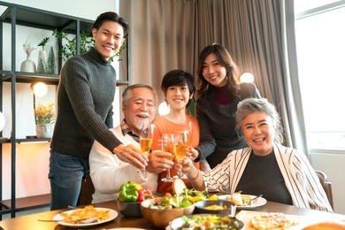 asian multi generation grandparent grandchild happiness joyful dinner together at home,holidays, celebration and people concept - happy friends with sparklers having christmas thanksgiving dinner 