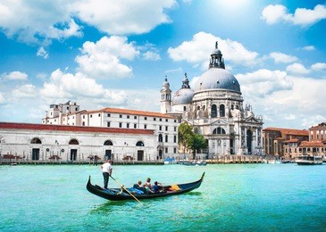 traditional gondola on canal grande with basilica di santa maria della salute in the background, venice, italy