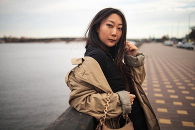 pretty young asian woman lifestyle with winter clothing along a seawall on the bay with a downtown skyline.