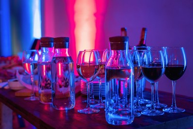 glasses of wine and snacks on a bar table in night club blue and red neon lights. party or nightlife entertainment with copy space