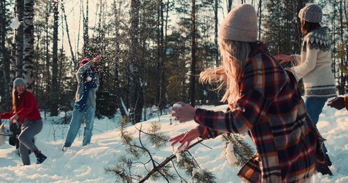 idyllic cinematic shot, happy diverse friends enjoying fun snowball fight at snowy winter forest with dog slow motion.