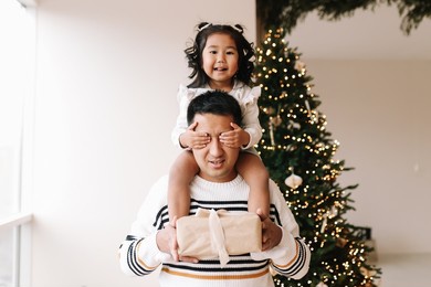 happy funny asian dad and little daughter child have fun celebrating christmas and new year's holiday in the decorated room of the house. selective focus